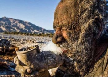 Аму Хаджи занимается любимым делом — курит сухой навоз через металлическую трубу. Фото: IRNA