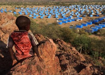 Мальчик сидит на вершине холма с видом на лагерь беженцев недалеко от границы Чада и Судана, 9 ноября 2023 года. Фото: Эль Тайеб Сиддиг / Reuters