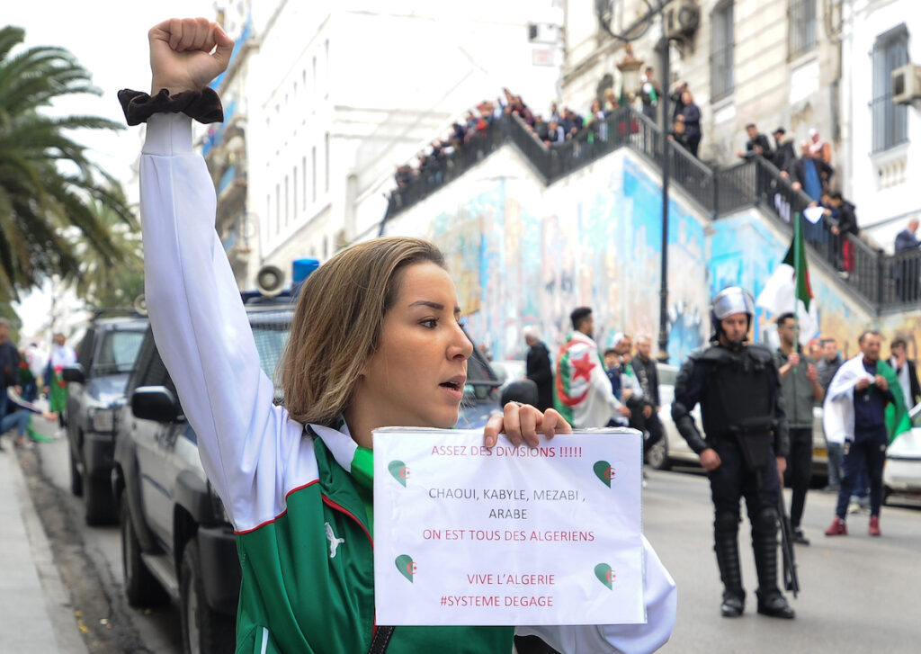 Митинг совпал с Международным женским днем. Алжирские женщины вышли на демонстрации. Протестующая держит в руках табличку с надписью: "Хватит разделений... Мы все алжирцы". Фото: MEE/Mohamed Kaouche