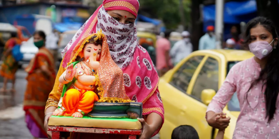 В Индии женщина несет идол индуистского бога Ганеша. 22 августа 2020 года. Фото: Reuters