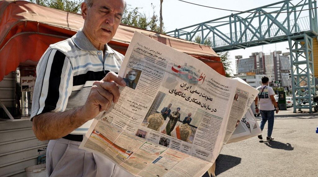 Иранец в Тегеране читает газету Etalaat с заголовком «Иран — новый член Шанхайской организации сотрудничества». 18 сентября 2021 года. Фото: AFP