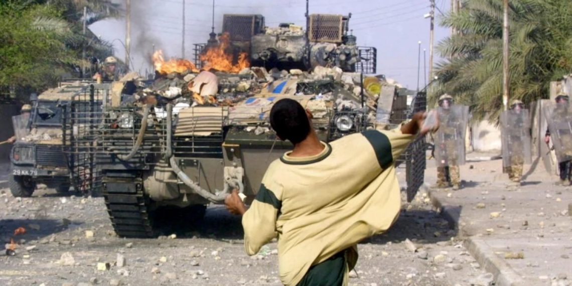 Житель Ирака бросает камни в британских солдат во время столкновений в городе Басра на юге Ирака. 19 сентября 2005 года. Фото: AFP