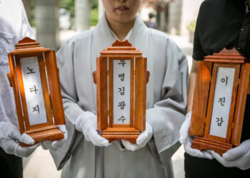 Буддийская монахиня и сотрудники Good Nanum держат таблички с именами трех умерших в одиночестве людей перед их кремацией. Фото: Джин Чунг.