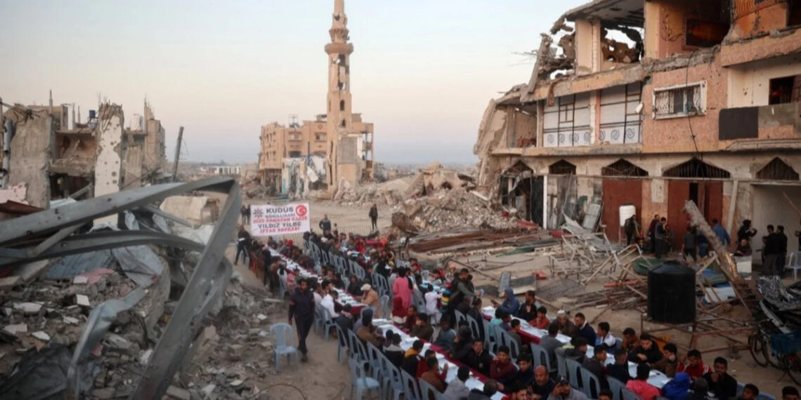 Палестинцы собрались на совместную трапезу в честь окончания поста во время Рамадана на фоне разрушений в лагере беженцев Нусейрат в секторе Газа. Фото: AFP