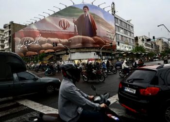 Люди едут на мотоциклах мимо билборда с изображением Моджтабы Хаменеи в Тегеране. Фото: Wana News Agency / Reuters